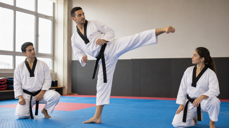 Instructor de Taekwondo demostrando patada tecnica en dojang con practicantes observando