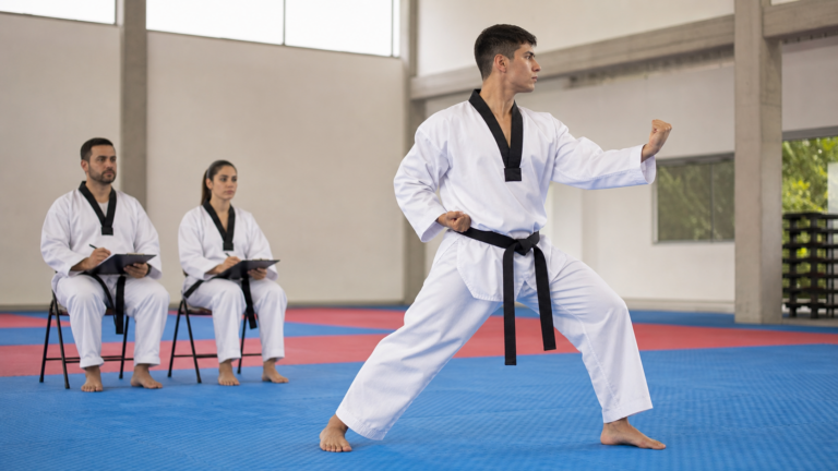 Practicante ejecutando Poomsae mientras instructores evaluan criterios tecnicos